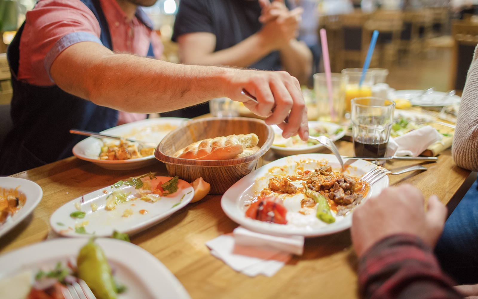 Group dining at a restaurant with shared dishes and drinks on a wooden table.