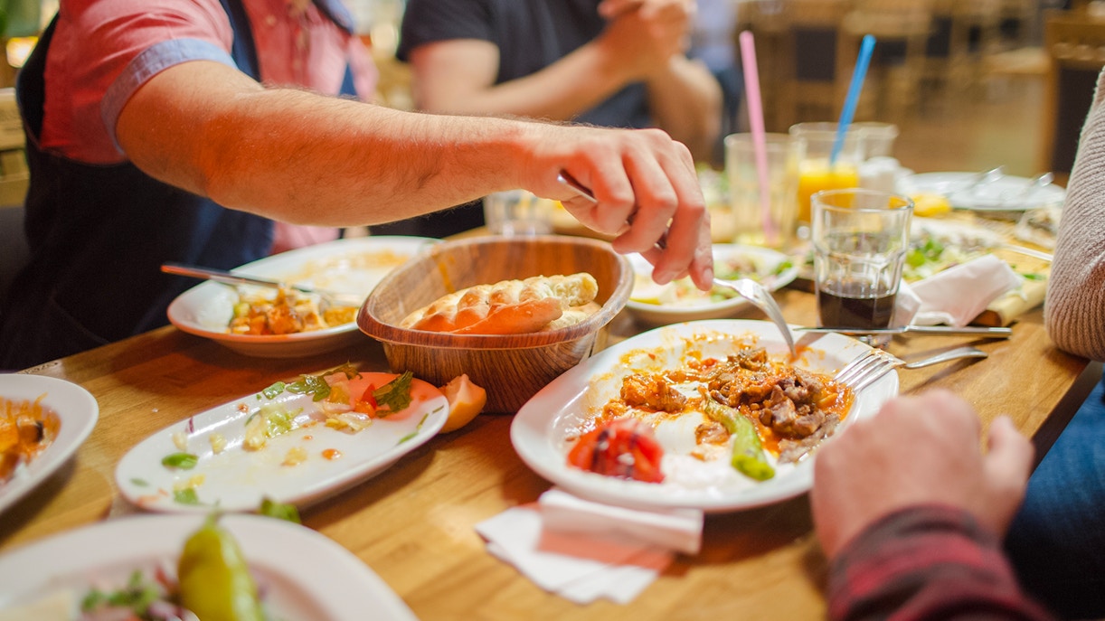 Group dining at a restaurant with shared dishes and drinks on a wooden table.