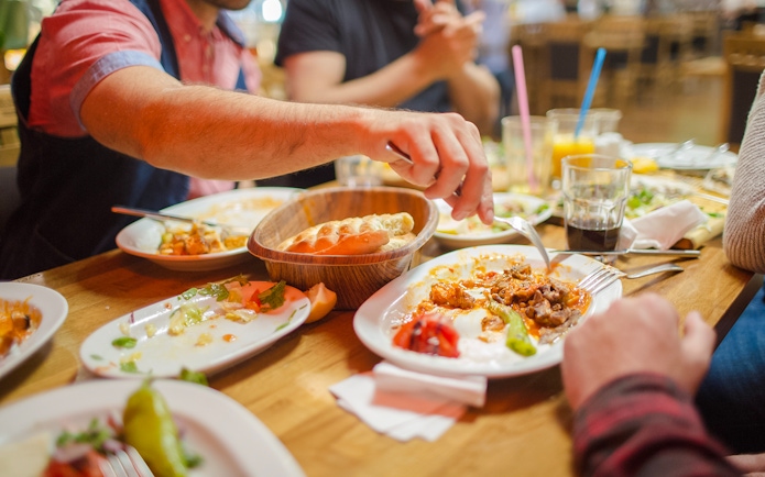 Group dining at a restaurant with shared dishes and drinks on a wooden table.