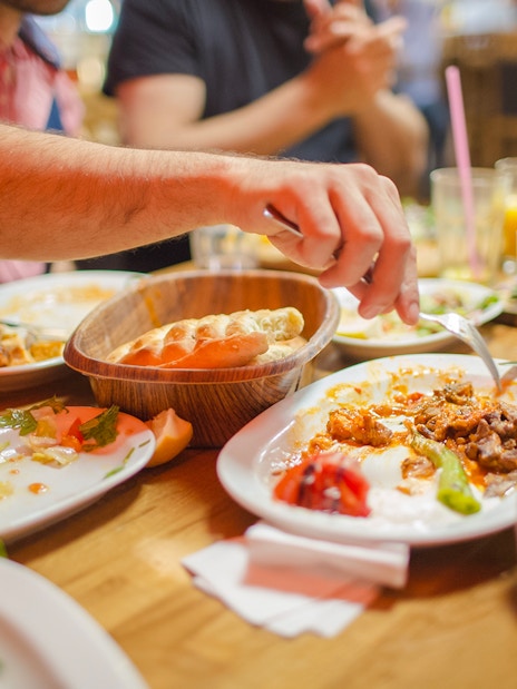 Group dining at a restaurant with shared dishes and drinks on a wooden table.