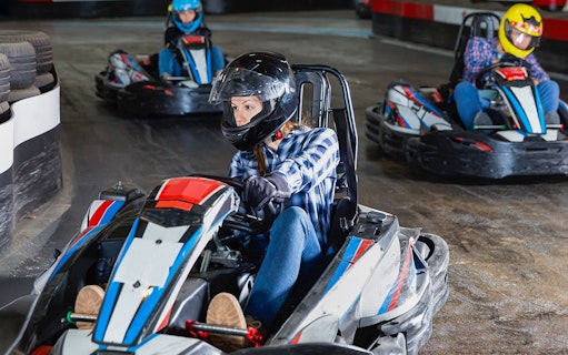 People racing go-karts on an indoor track.