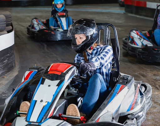 Indoor go-karting track with racers navigating sharp turns in a competitive setting.