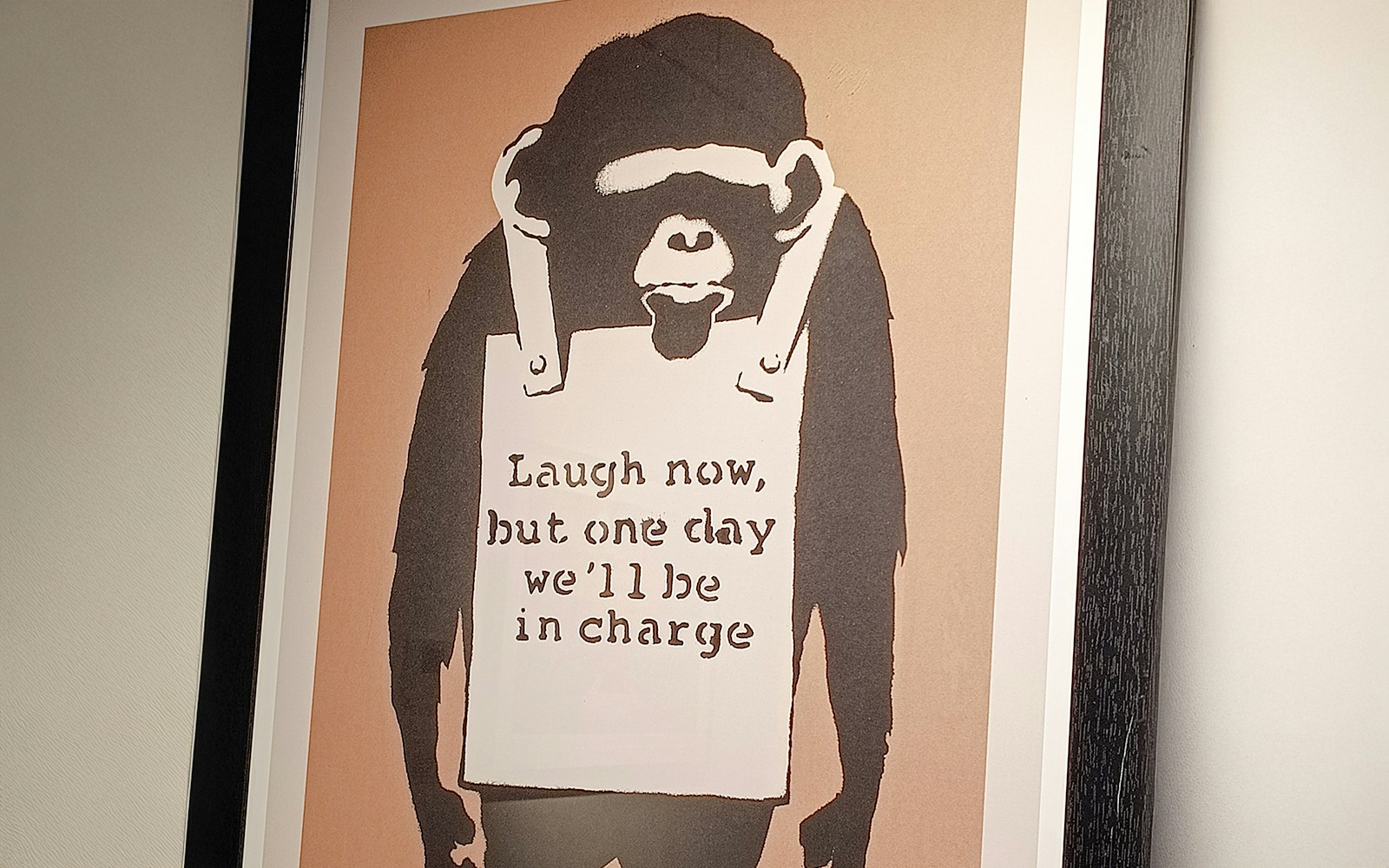 Banksy artwork of a chimpanzee with a sign reading "Laugh now, but one day we'll be in charge.