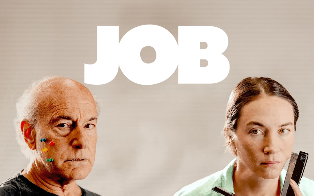 Two people with serious expressions, one with colorful pins on face, under the word 'JOB'.