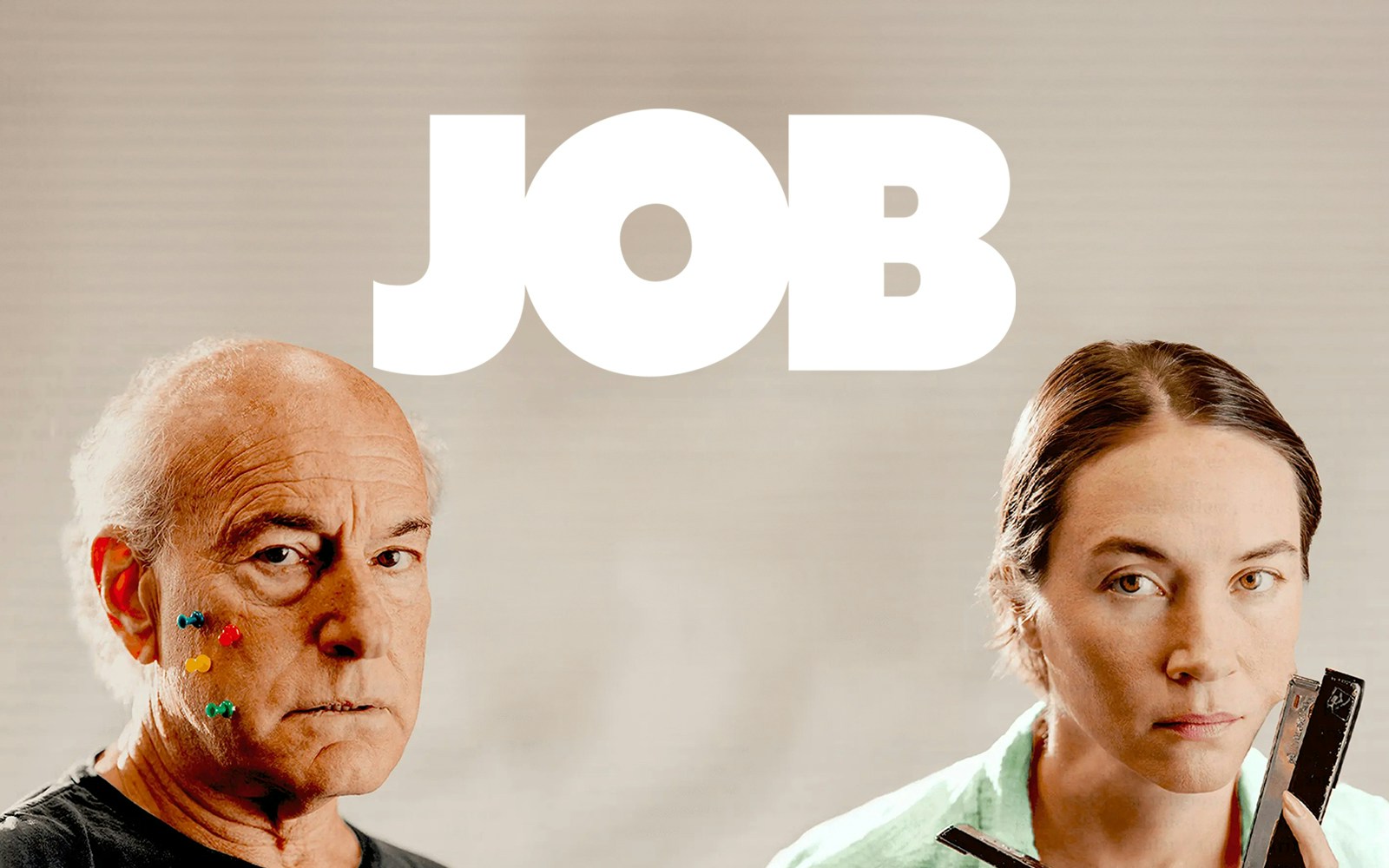 Two people with serious expressions, one with colorful pins on face, under the word 'JOB'.