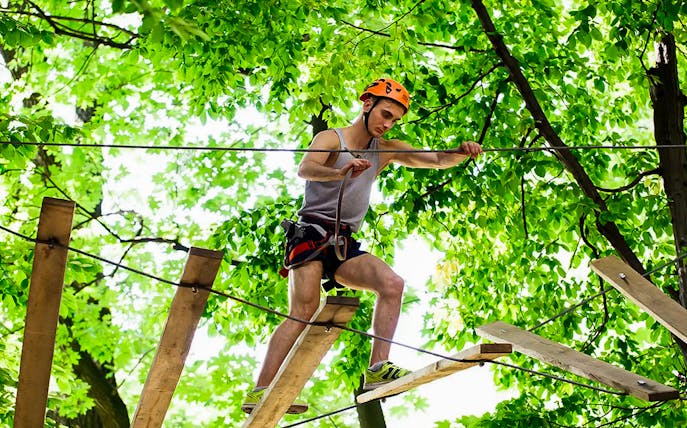 Person navigating a treetop rope course at Montes de Laboreiro.