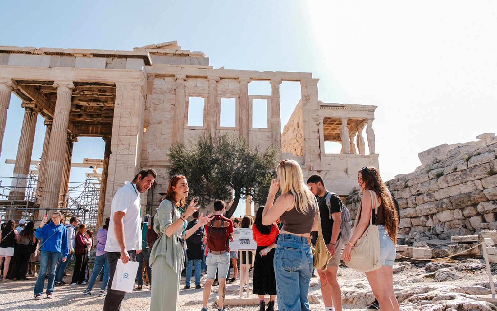 Guided group tour at the Parthenon in Athens, Greece, with tourists listening to a guide.