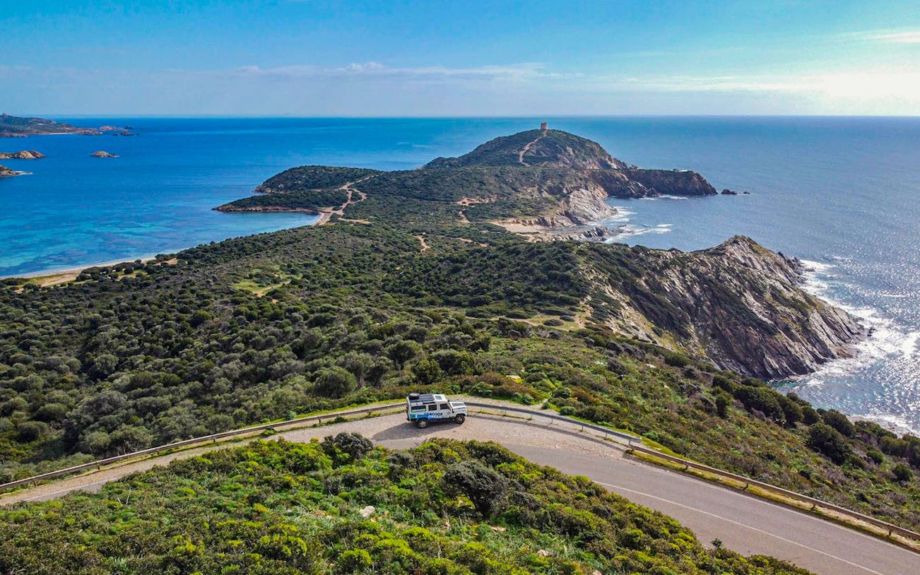 4x4 vehicle on coastal road with view of Chia's beaches and mountains, Cagliari tour.