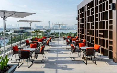 Rooftop dining area with red-cushioned chairs overlooking Dubai skyline at Gastronomy Buffet Dinner Experience.