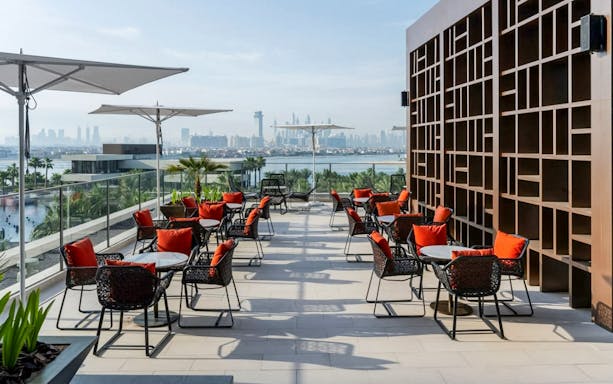 Rooftop dining area with red-cushioned chairs overlooking Dubai skyline at Gastronomy Buffet Dinner Experience.