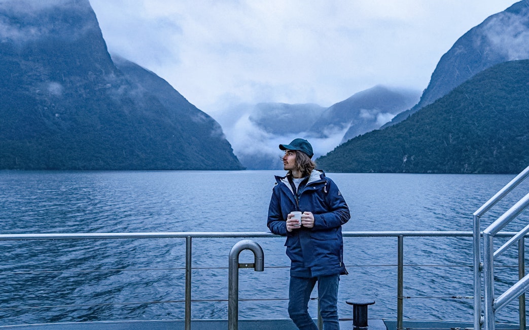 Cruise passenger on deck with Doubtful Sound fjord view, Te Anau.