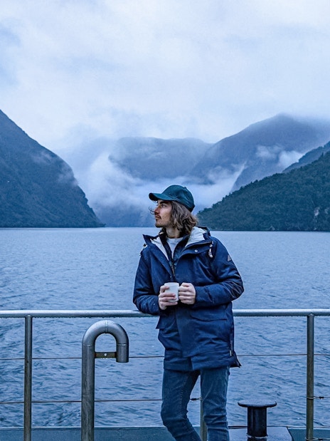 Cruise passenger on deck with Doubtful Sound fjord view, Te Anau.