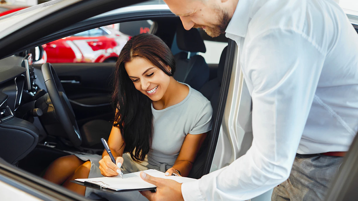 Person signing car rental agreement inside vehicle.