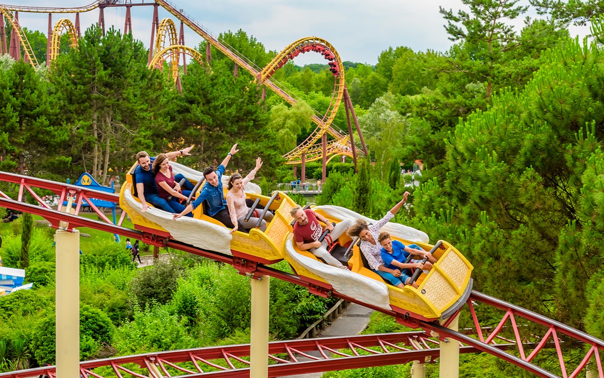 Roller coaster ride at Astérix Park with people enjoying the thrill amidst lush greenery.