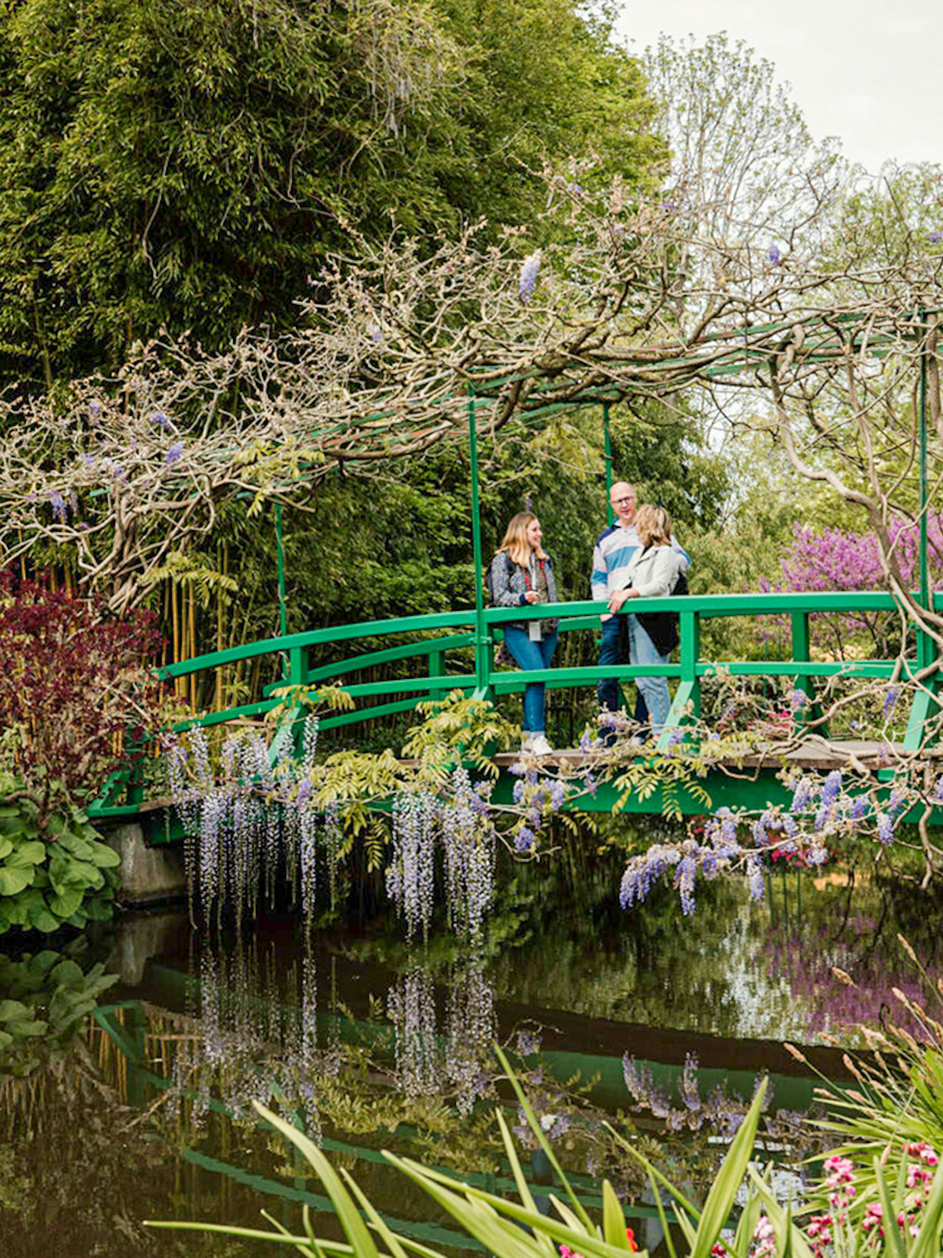 Visitors on Monet's Japanese bridge in Giverny garden during Musée d'Orsay tour.