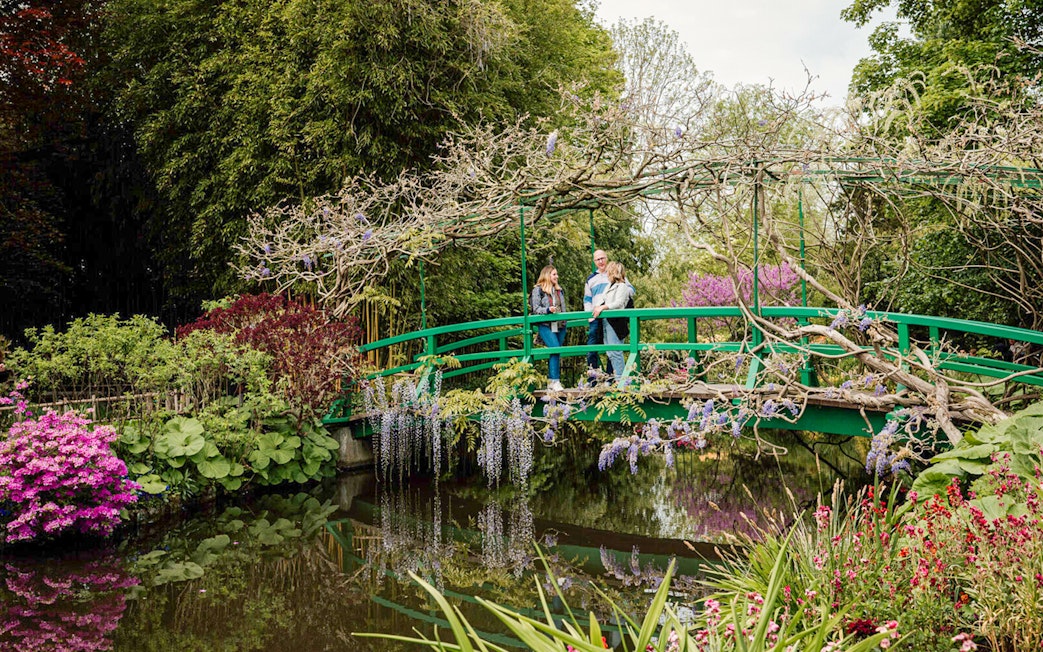 Visitors on Monet's Japanese bridge in Giverny garden during Musée d'Orsay tour.