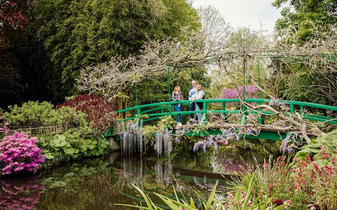 Visitors on Monet's Japanese bridge in Giverny garden during Musée d'Orsay tour.