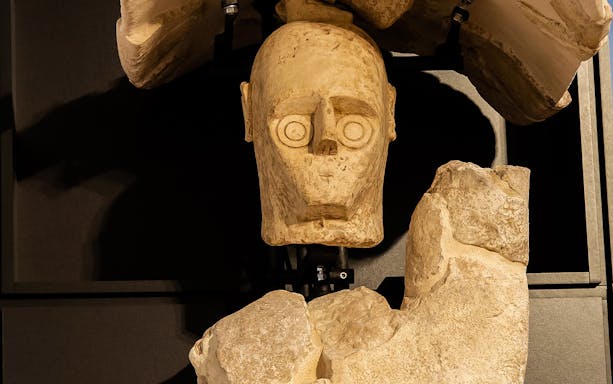 Stone sculpture of a head in Cagliari's historic center museum exhibit.