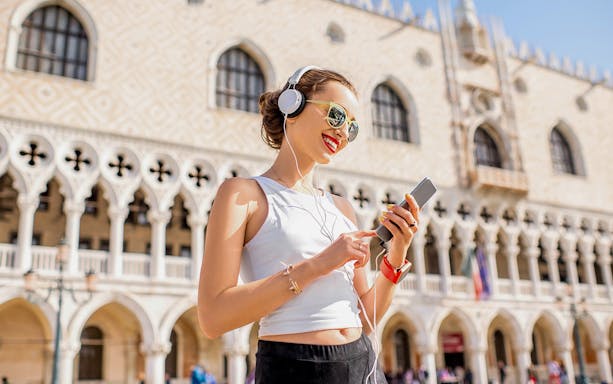 Person enjoying audio guide in front of Doge's Palace, Venice.