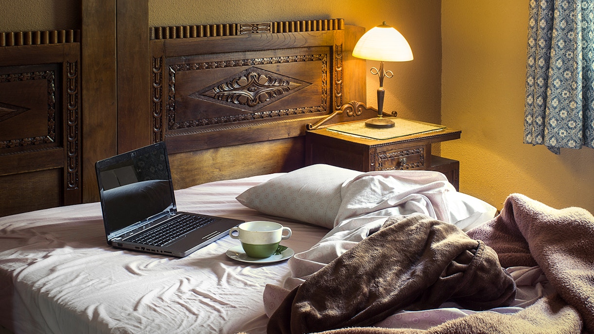 Rustic hotel room with wooden beams and cozy bedding in a countryside setting.