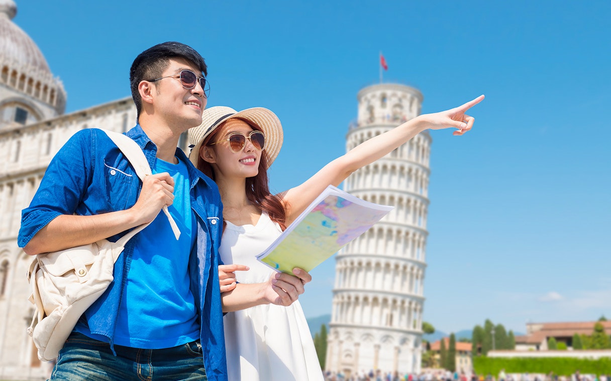 Couple with map on guided tour at Tower of Pisa, Italy.