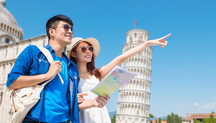 Couple with map on guided tour at Tower of Pisa, Italy.
