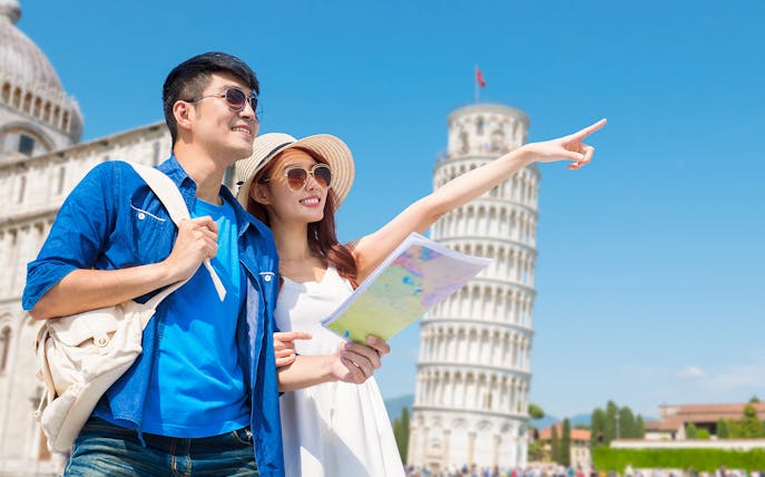 Couple with map on guided tour at Tower of Pisa, Italy.