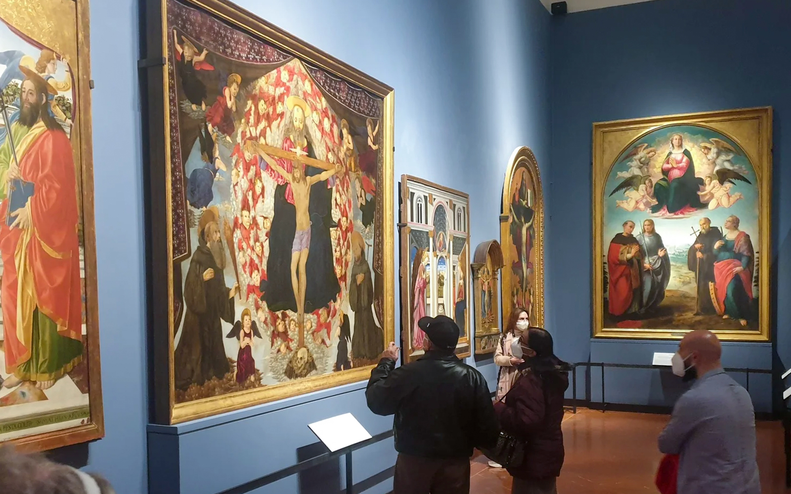Visitors viewing Alesso Baldovinetti's "The Trinity and Saints Benedict and Giovanni Gualberto" at Accademia Gallery, Florence.