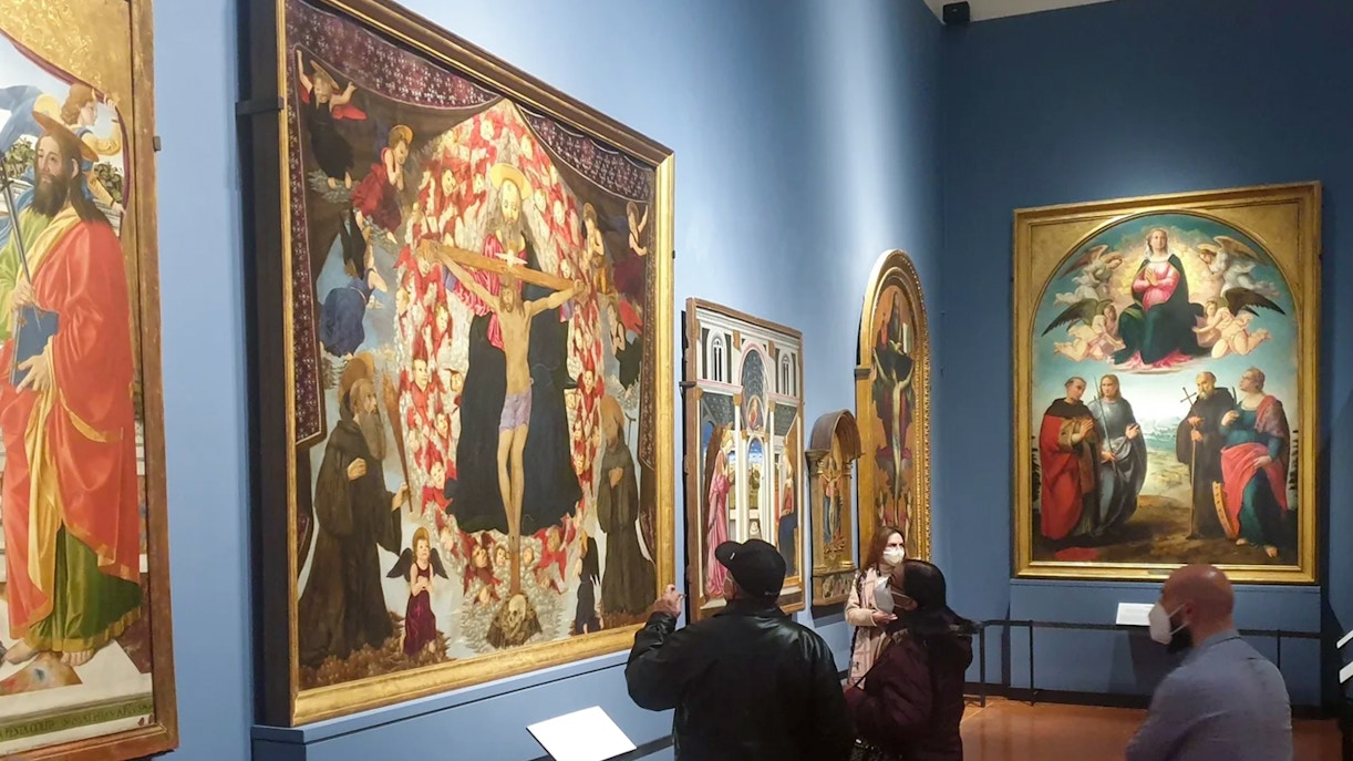 Visitors viewing Alesso Baldovinetti's "The Trinity and Saints Benedict and Giovanni Gualberto" at Accademia Gallery, Florence.