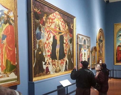 Visitors viewing Alesso Baldovinetti's "The Trinity and Saints Benedict and Giovanni Gualberto" at Accademia Gallery, Florence.