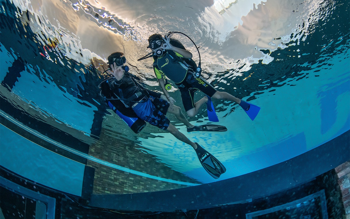 Scuba divers exploring Deep Dive Dubai pool.