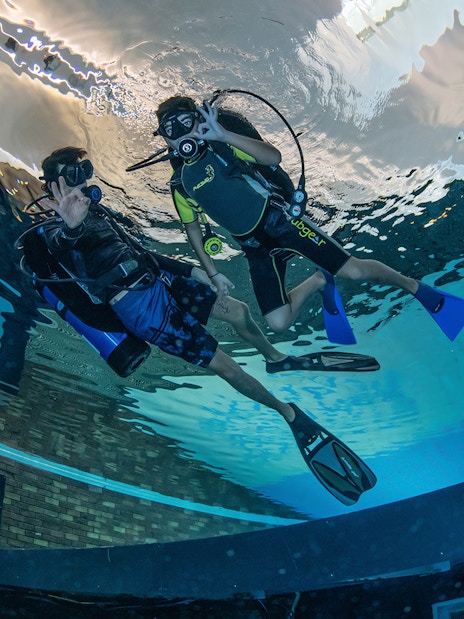 Scuba divers exploring Deep Dive Dubai pool.