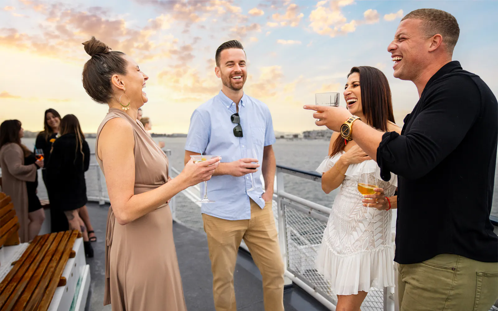 Guests enjoying drinks on the deck during sunset on the San Diego Signature Dinner Cruise.