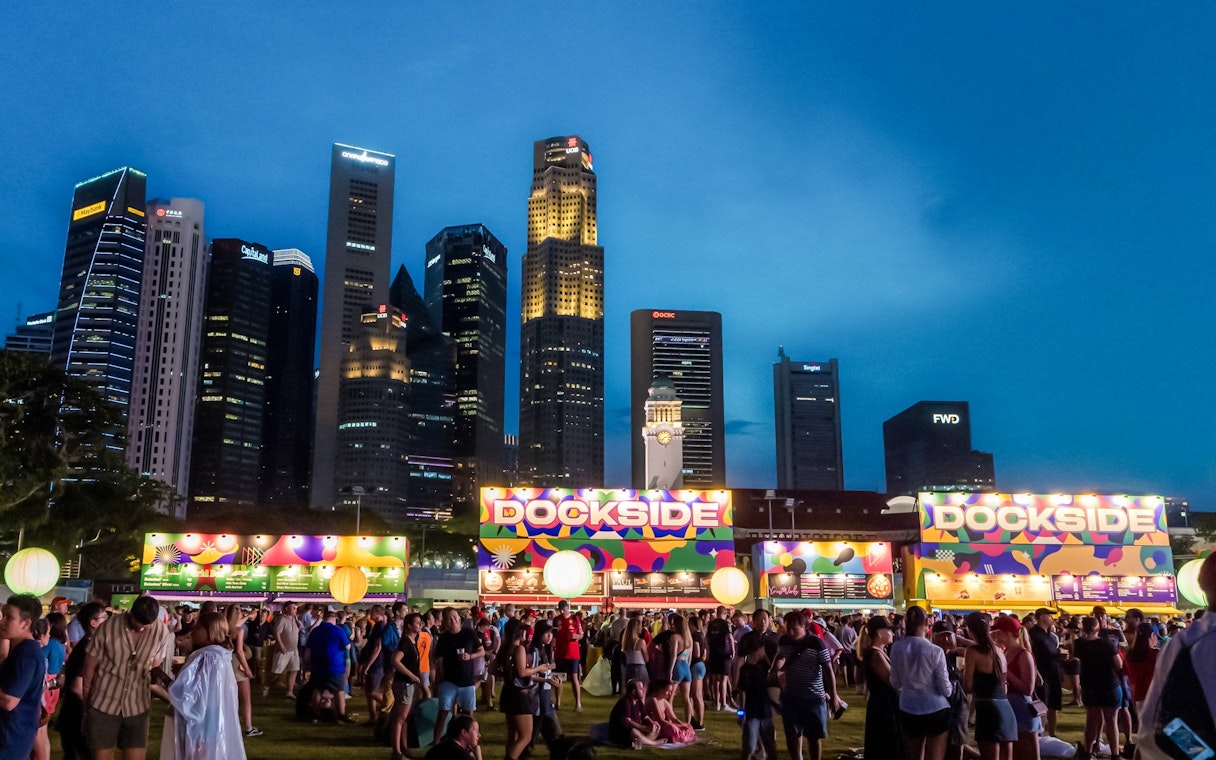 Crowd at Dockside event in Zone 4 with city skyline at dusk.