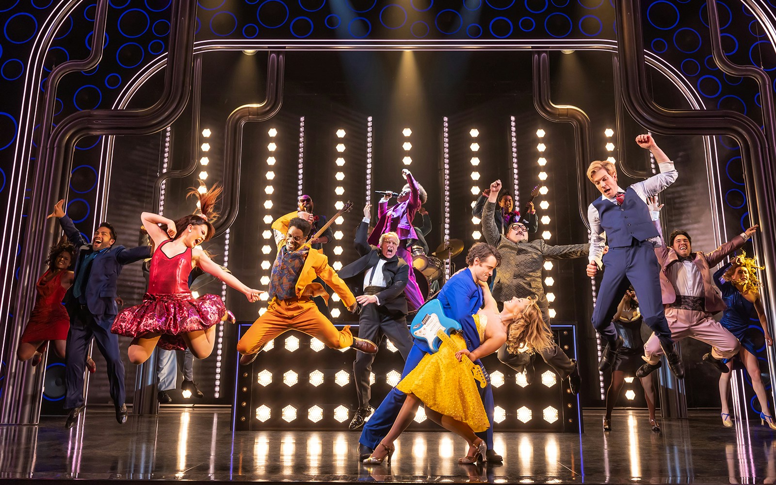 Performers dancing energetically on stage during "The Heart of Rock and Roll" musical.