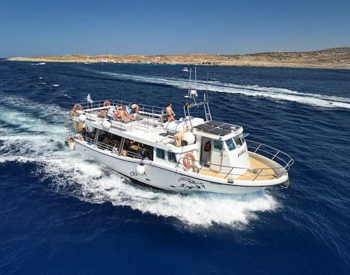 Cruise boat on Blue Lagoon Malta with passengers enjoying the view.