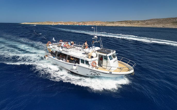 Cruise boat on Blue Lagoon Malta with passengers enjoying the view.