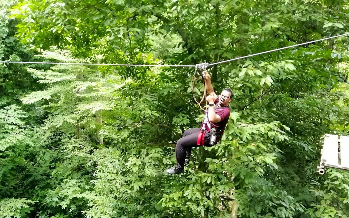 Person ziplining through lush forest at Skytrex Adventure Langkawi.
