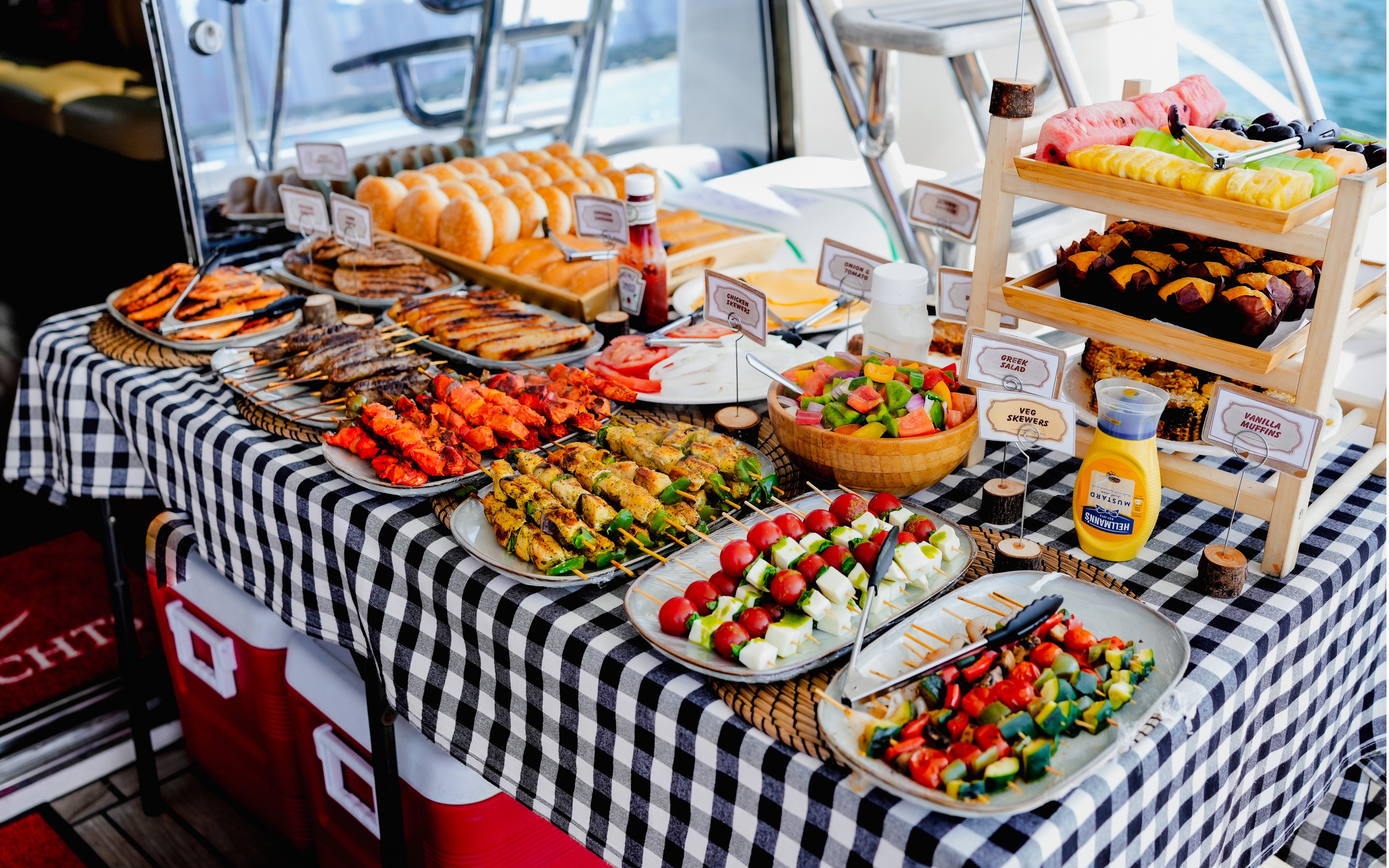 Buffet spread on a luxury yacht in Dubai Harbour featuring skewers, salads, and fresh fruit.