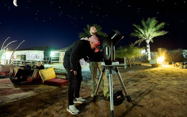 Stargazing with telescope during private night safari in desert camp.