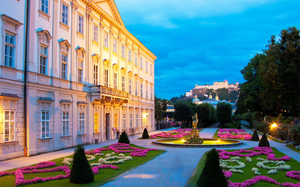 Mirabell Palace gardens at dusk, Salzburg, with Hohensalzburg Fortress in the background.