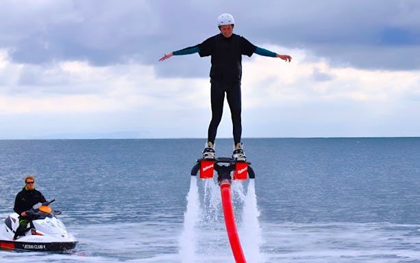 Person flyboarding over the sea near Hurghada with a jet ski in the background.