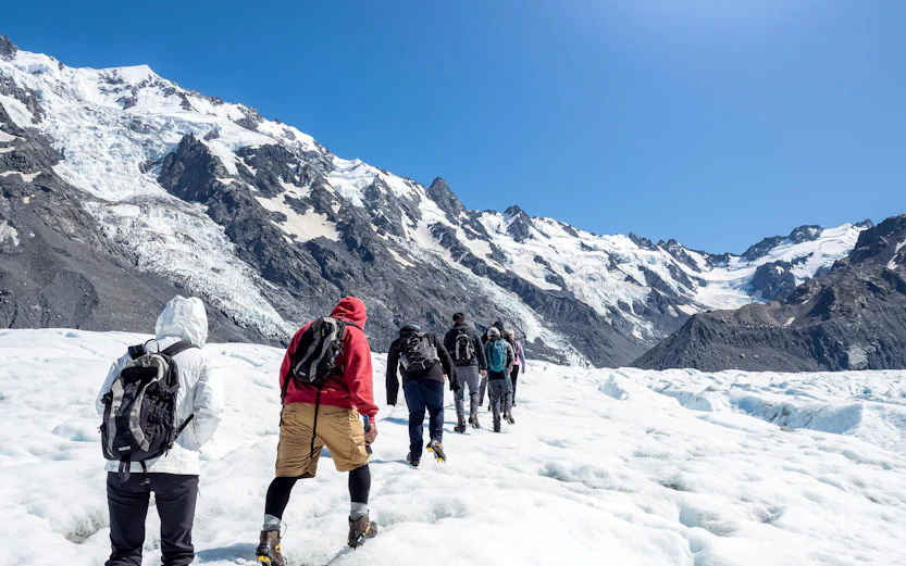 Hikers trekking on Tasman Glacier in Mount Cook National Park, New Zealand.