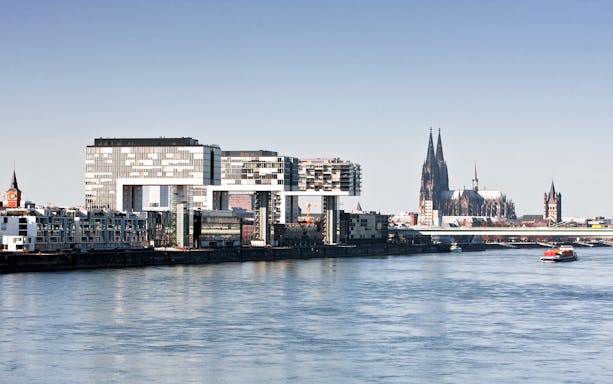 Cologne cityscape with Rhine River, featuring Cologne Cathedral and modern buildings.