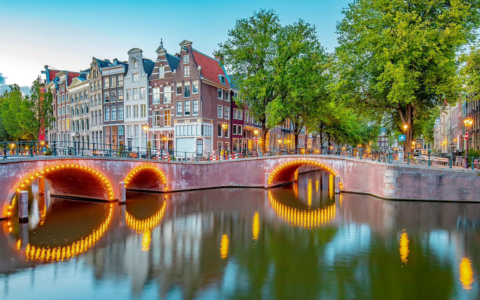 Jordaan district canal view with illuminated bridge and traditional houses in Amsterdam.