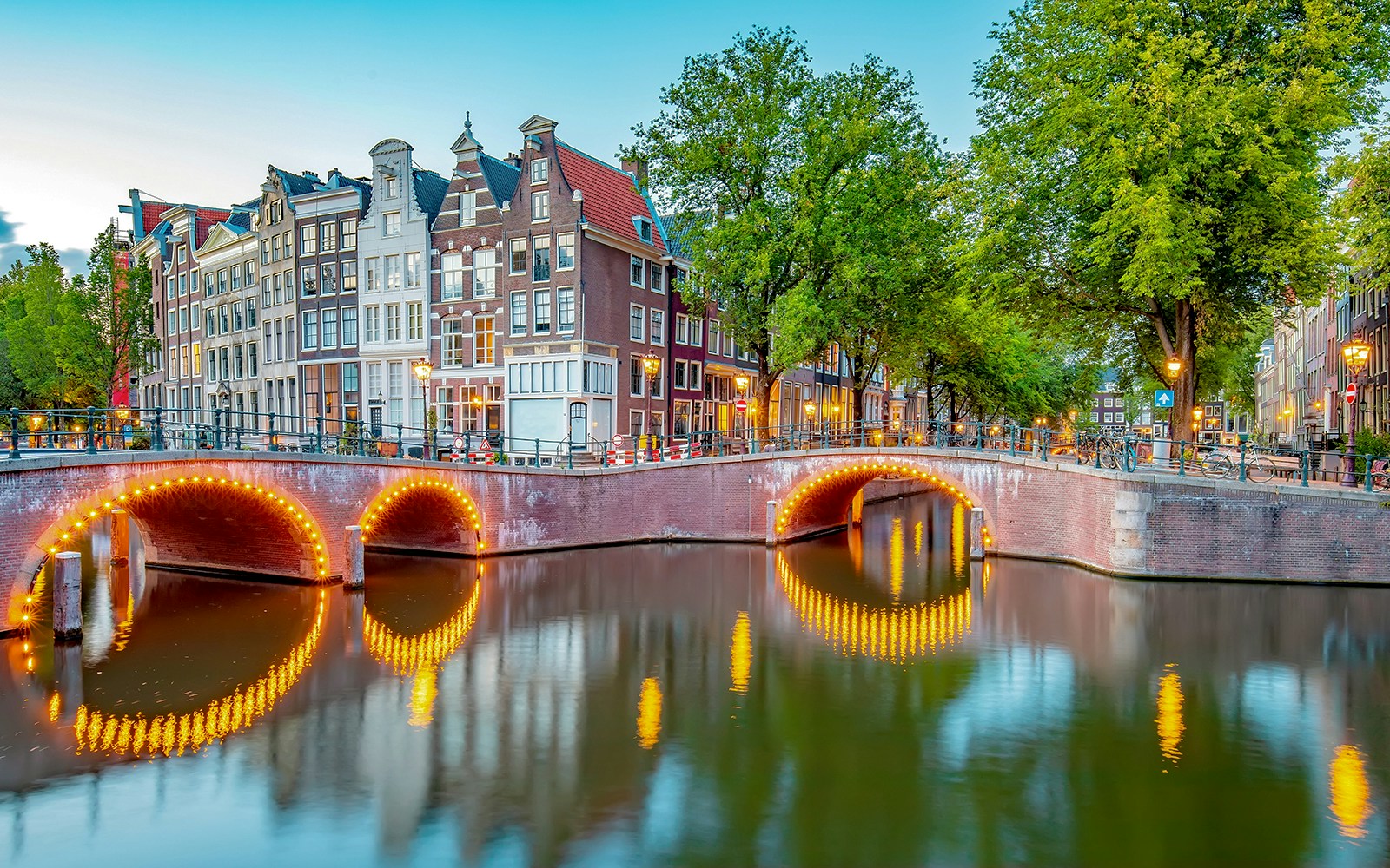 Jordaan district canal view with illuminated bridge and traditional houses in Amsterdam.