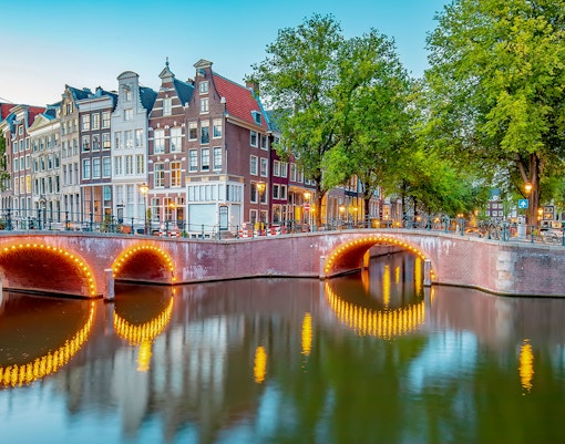 Jordaan district canal view with illuminated bridge and traditional houses in Amsterdam.