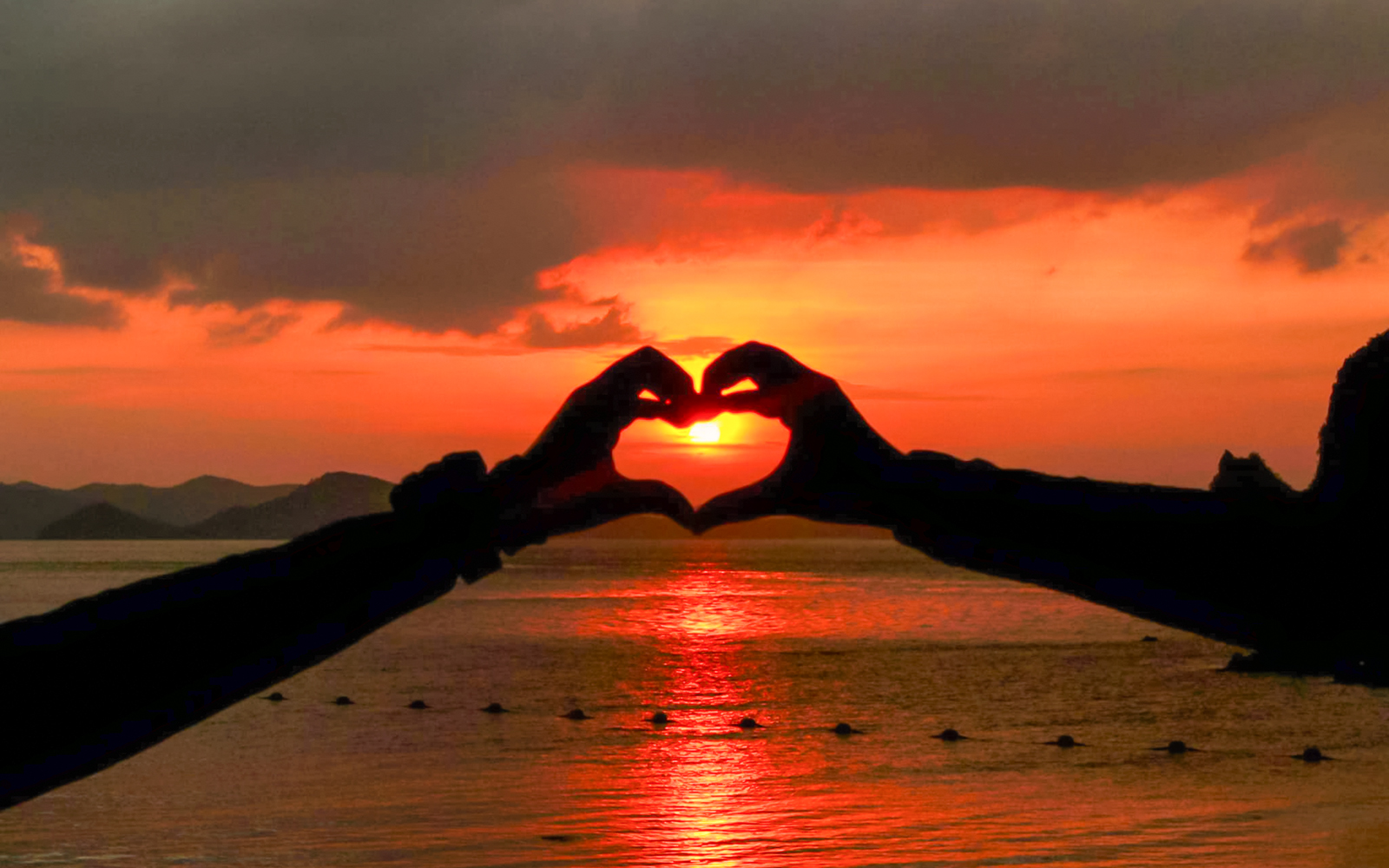 Couple forming heart shape with hands at sunset during Krabi 7 Islands tour.