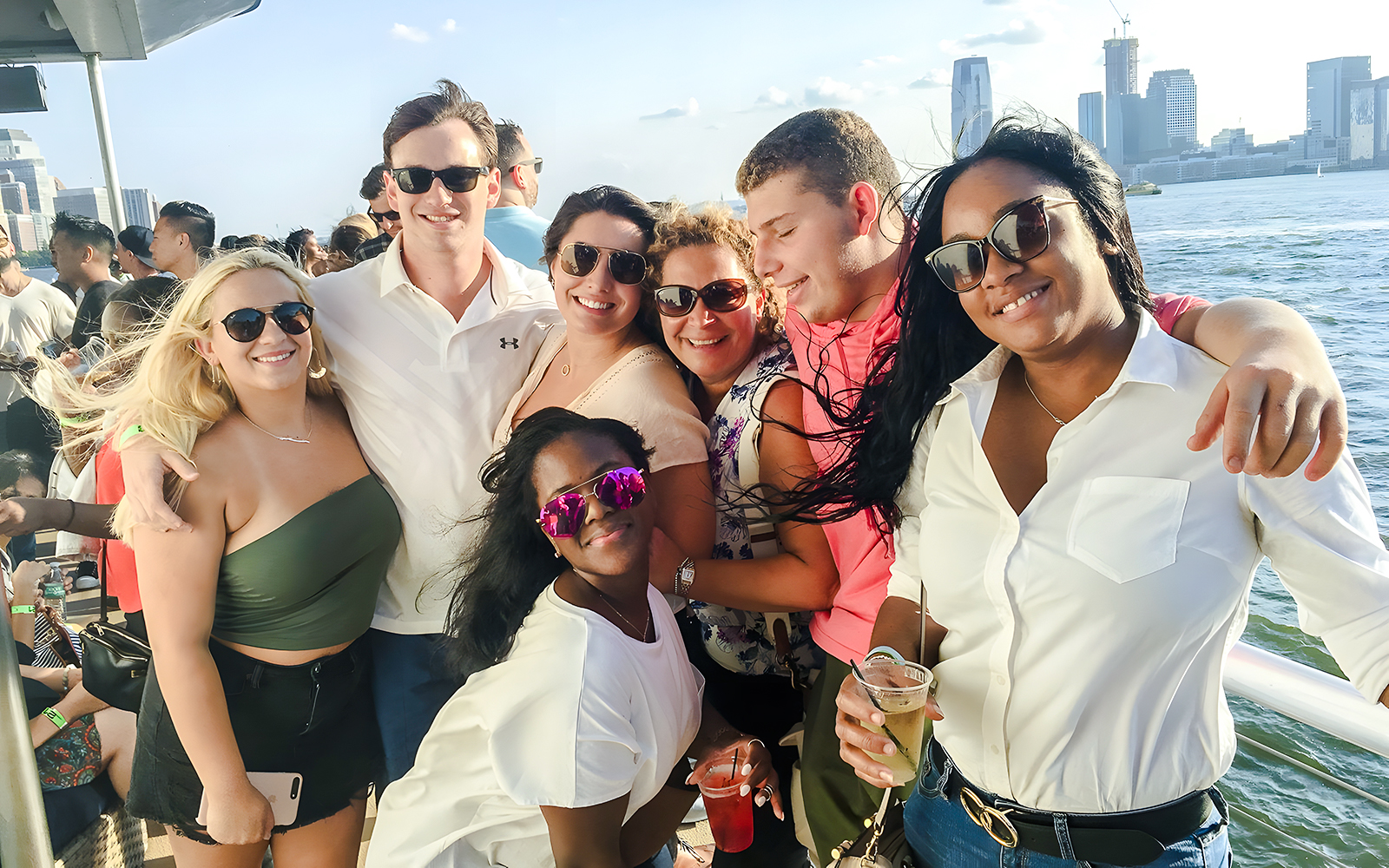 Group enjoying a cruise with New York City skyline in the background.
