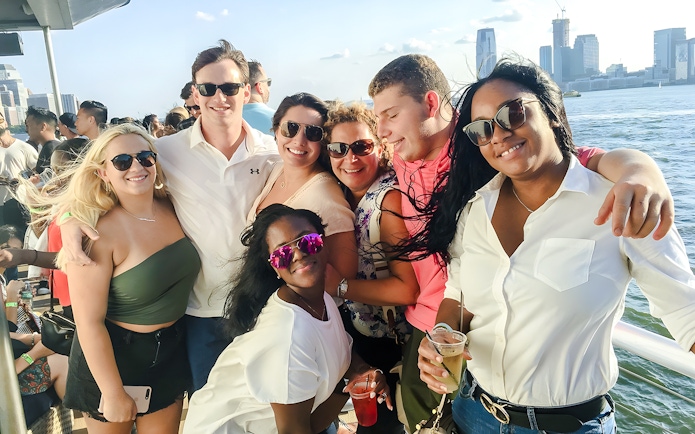 Group enjoying a cruise with New York City skyline in the background.